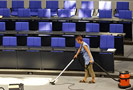 Bild: Reinigungskraft saugt Fußboden