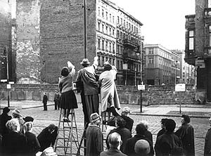 Fotografie: Auf Leitern stehend winken Westberliner ihren Angehörigen zu.