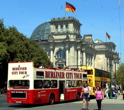 Zwei Busse und mehrere Touristen stehen vor dem Reichstagsgebäude.