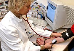 In einer Arztpraxis misst eine Ärztin bei einer Patienten den Blutdruck.