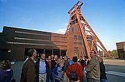Besuchergruppe steht vor dem Doppelbock-Fördergerüst des Schachts XII der Essener Zeche Zollverein.