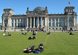 Besucher liegen auf dem Platz der Republik, im Hintergrund Reichstagsgebäude, Klick vergrößert Bild