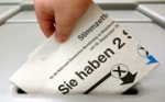 Ein Stimmzettel wird in eine Wahlurne gesteckt.