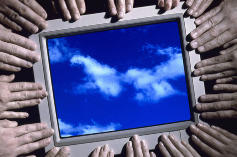 Viele Hände um einen Bildschrim, der blauen Himmel zeigt.