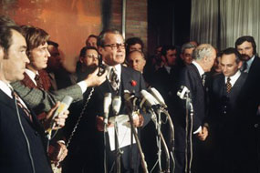 Von Journalisten umringt tritt Bundeskanzler Willy Brandt vor die Mikrofone.
