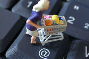 Figur schiebt Einkaufswagen auf einer Computertastatur