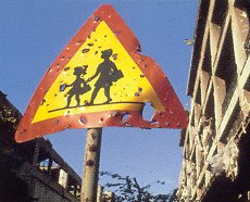 von Gewehrkugeln durchlöchertes Straßenschild, das auf Schulkinder hinweist