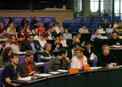 Foto: Jugendliche sitzen im Plenarsaal, reden miteinander und hören zu