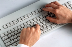 Zwei Hände schreiben auf einer Computertastatur.