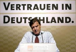 Foto: Bundeskanzler Gerhard Schröder während einer Rede. Im Hintergrund ein Wahlslogan an der Wand