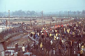Fotografie, 13. November 1976: Demonstranten gegen den Kernkraftwerksbau in Brokdorf stehen mit Transparenten vor dem Baugelände, das mit Stacheldrahtzaun und Polizeiaufgebot abgesichert ist.