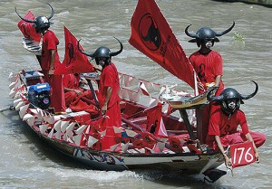 Gruppe Indonesier mit gehörnten Helmen in roten Kahn 