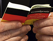 Bild: Hände halten Grundgesetzbuch im Miniaturformat.