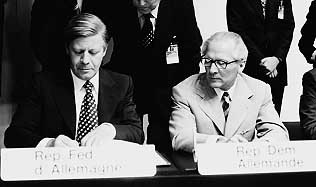 Bundeskanzler Helmut Schmidt unterzeichnet die Schlussakte, der DDR-Staatsratsvorsitzende Erich Honecker schaut ihm dabei zu.