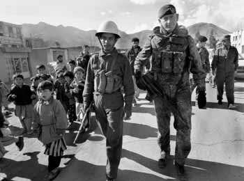 Afghanische Kinder und Jugendliche begleiten einen deutschen Soldaten und einen afghanischen Polizisten bei der gemeinsamen Patrouille durch einen Vorort von Kabul.