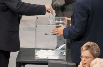 Stimmabgabe: Der Umschlag mit dem Stimmzettel landet in der durchsichtigen Wahlurne.
