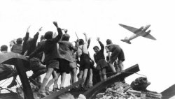 Fotografie, 1848: West-Berliner Jungen, die auf einem Trümmerberg stehen, begrüßen winkend ein US-amerikanisches Transportflugzeug, das Versorgungsgüter nach West-Berlin bringt.