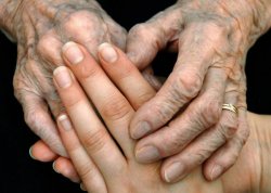 Fotografie: Eine Betreuerin hält die Hände einer alten Frau