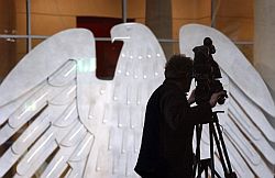 Cameraman sur la tribune de presse en salle plénière du Bundestag allemand. Au second plan, l'aigle du Bundestag allemand.
