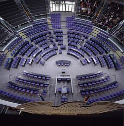 Vue d'en haut, la salle plénière du Bundestag allemand : les sièges sont regroupés par groupes parlementaires.