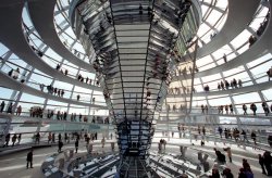 Foto: Lichtelement in der Kuppel des Reichstagsgebäudes, viele Leute laufen drum herum und lesen auf Infotafeln