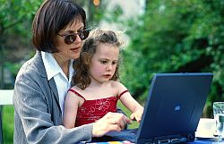 Berufstätige Mutter mit Tochter arbeitend an Laptop im Garten