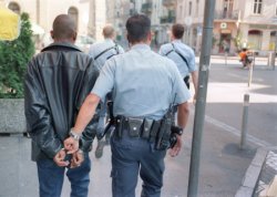 Foto: Polizist führt einen Häftling in Handschellen ab