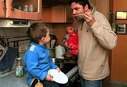 Vater mit zwei Kleinkindern am Küchenherd