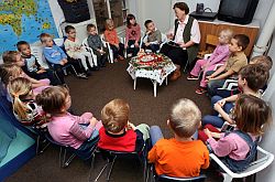 Kinder einer Tagesstätte hören einer 'Lese-Oma' zu