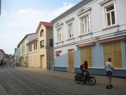Geschäftsstraße in Bad Doberan, Fensterläden sind mit Holzbrettern geschützt