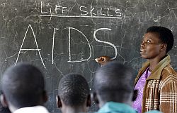 Eine afrikanische Lehrerin schreibt das Wort Aids an die Tafel eines Klassenzimmers