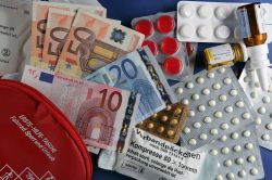 Euro-Geldscheine liegen zwischen Tablettenpackungen und medizinischen Hilfsmitteln