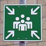 Einen Sammelplatz (auch Meeting Point) kennzeichnet diese grüne Hinweistafel mit dem Symbol einer Gruppe von Menschen