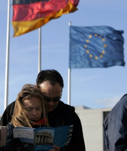 Foto: Besucher lesen eine Broschüre auf dem Dach des Reichstagsgebäudes