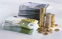 Neben Bündeln mit Zwanzig- und Hundert-Euro-Banknoten stehen Säulen aus gestapelten Euro- und Centmünzen