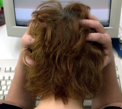 Eine Frau sitzt vor dem Computer und rauft sich die Haare.