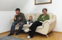 Familie sitzt genervt auf Sofa