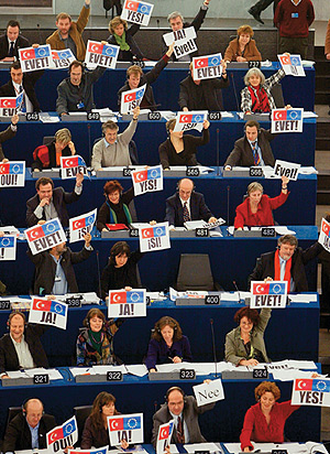 Abgeordnete des Europäischen Parlaments im Plenarsaal halten Plakate mit ihrem Votum in die Höhe.