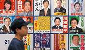 Junge vor japanischen Wahlplakaten