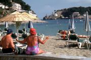 Mehrere Personen sitzen am Strand.