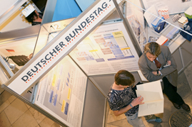 Besucher liest vor einer Tafel der Wanderausstellung des Bundestages in einem Buch