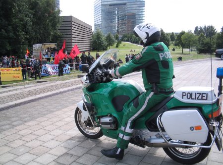 Ein Polizist auf einem Motorrad beobachtet eine Demonstration.
