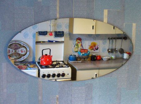 In einem Spiegel an der Wand sind Küchenutensilien der 60er Jahre (Herd, Schrank etc.) sichtbar.