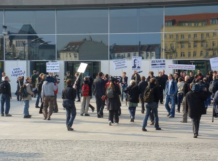 Leute demonstrieren mit Transparenten vor dem Bundespressamt.