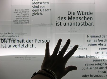 Eine Hand vor den Artikeln des Grundgesetzes.