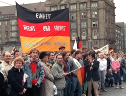 In Dresden stehen am 19.12.1989 Bürger mit Deutschlandfahnen und Transparenten und fordern "Einheit, Recht und Freiheit - Deutschland einig Vaterland".