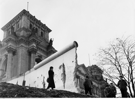 Frau vor der durchbrochenen Berliner Mauer Anfang 1990, im Hintergrund das Reichstagsgebäude