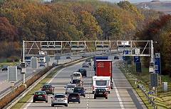 Foto: Fahrzeuge auf einer Autobahn unterqueren eine Maut-Station