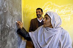 Afghanin schreibt einen englischen Text während eines Englisch-Kurses in der Lehrerausbildung im afghanischen Kundus an eine Tafel