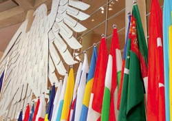 Internationale Fahnen vor dem Bundestagsadler im Plenarsaal